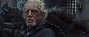 Movie still from “Snow White and the Huntsman” (2012), directed by Rupert Sanders – An old man with a beard and a chain around his neck; Close Up shot, Low angle