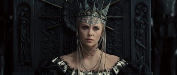 Movie still from “Snow White and the Huntsman” (2012), directed by Rupert Sanders – A woman wearing a metal crown with spikes on her head; Close Up shot, Low angle
