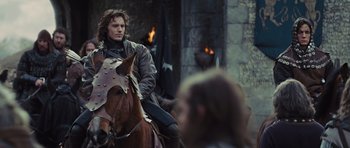 Movie still from “Snow White and the Huntsman” (2012), directed by Rupert Sanders – A man on a horse in front of a stone wall; Medium shot, Over the shoulder angle