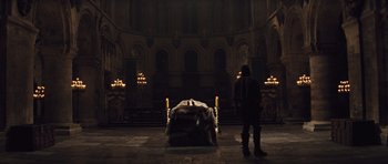 Movie still from “Snow White and the Huntsman” (2012), directed by Rupert Sanders – A man standing in front of an empty bed in a dark room; Wide shot, High angle