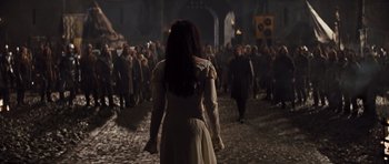 Movie still from “Snow White and the Huntsman” (2012), directed by Rupert Sanders – A woman in a white dress walking in front of a group of people; Wide shot, Over the shoulder angle