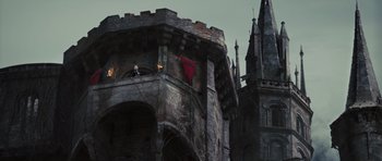 Movie still from “Snow White and the Huntsman” (2012), directed by Rupert Sanders – A man standing on the side of a building next to a tower; Extreme Wide shot, Low angle