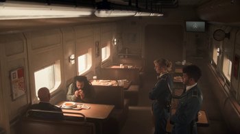 Movie still from “Snowpiercer” (2020), created by Graeme Manson – A group of people standing around a table in a room; Wide shot, High angle