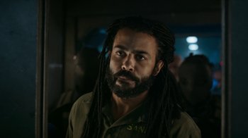 Movie still from “Snowpiercer” (2020), created by Graeme Manson – A man with dreads is looking at the camera; Close Up shot, Over the shoulder angle