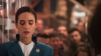 Movie still from “Snowpiercer” (2020), created by Graeme Manson – A woman in a blue jacket with her eyes closed in front of a group of people; Close Up shot, Over the shoulder angle