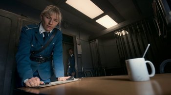 Movie still from “Snowpiercer” (2020), created by Graeme Manson – A woman in a blue uniform looking down at a laptop; Medium shot, Low angle