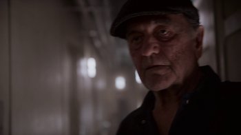 Movie still from “Snowpiercer” (2020), created by Graeme Manson – An older man wearing a hat and looking at the camera; Close Up shot, Over the shoulder angle