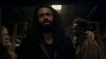 Movie still from “Snowpiercer” (2020), created by Graeme Manson – A man with dreadlocks is looking at the camera; Close Up shot, Low angle