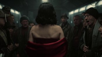 Movie still from “Snowpiercer” (2020), created by Graeme Manson – A group of people standing around a woman in a red dress; Medium shot, Over the shoulder angle