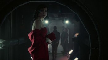 Movie still from “Snowpiercer” (2020), created by Graeme Manson – A woman in a red dress holding a book in a dark room; Medium shot, Low angle