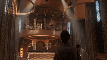 Movie still from “Snowpiercer” (2020), created by Graeme Manson – A man standing in front of a bar in front of a balcony; Wide shot, Low angle