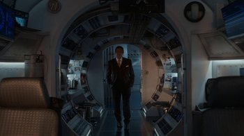 Movie still from “Snowpiercer” (2020), created by Graeme Manson – A man in a suit and tie standing in an archway; Wide shot, Over the shoulder angle