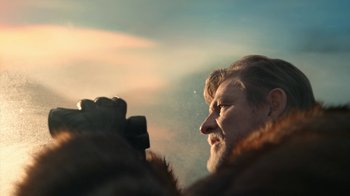 Movie still from “Snowpiercer” (2020), created by Graeme Manson – A man in a fur coat is taking a picture of the sky; Close Up shot, Low angle
