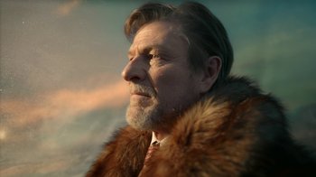 Movie still from “Snowpiercer” (2020), created by Graeme Manson – An older man wearing a fur coat and a tie; Close Up shot, Low angle