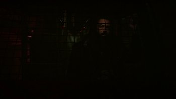Movie still from “Snowpiercer” (2020), created by Graeme Manson – A man standing in a dark room behind bars; Medium shot, Low angle