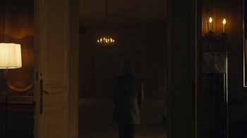 Movie still from “Mr. Robot” (2015), created by Sam Esmail – A man standing in a dark room with a chandelier hanging from the ceiling; Wide shot, Over the shoulder angle