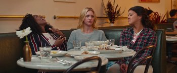 Movie still from “Someone Great” (2019), directed by Jennifer Kaytin Robinson – A group of people sitting at a table with plates of food on it; Medium shot, Over the shoulder angle