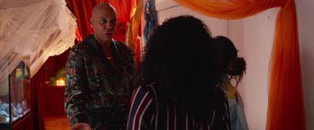 Movie still from “Someone Great” (2019), directed by Jennifer Kaytin Robinson – A man with a bald head standing in front of two women; Medium shot, Over the shoulder angle