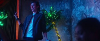 Movie still from “Someone Great” (2019), directed by Jennifer Kaytin Robinson – A man standing next to a lit up palm tree; Medium shot, Low angle