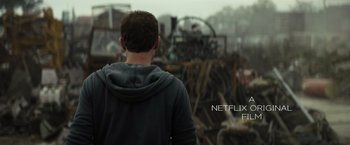 Movie still from “Spectral” (2016), directed by Nic Mathieu – A man standing in front of a pile of machinery; Medium shot, Over the shoulder angle