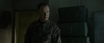 Movie still from “Spectral” (2016), directed by Nic Mathieu – A man in a military uniform standing in a room; Close Up shot, Over the shoulder angle