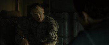Movie still from “Spectral” (2016), directed by Nic Mathieu – A man in a military uniform sitting in front of a wall; Close Up shot, Over the shoulder angle