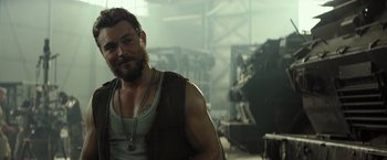 Movie still from “Spectral” (2016), directed by Nic Mathieu – A man in a tank top and a necklace; Close Up shot, Over the shoulder angle