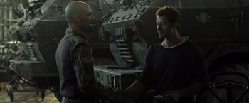 Movie still from “Spectral” (2016), directed by Nic Mathieu – Two men shake hands in front of a tank; Medium shot, Over the shoulder angle