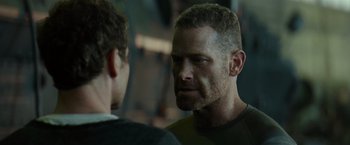 Movie still from “Spectral” (2016), directed by Nic Mathieu – A man is looking at another man in a dark room; Close Up shot, Over the shoulder angle