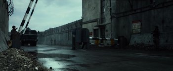 Movie still from “Spectral” (2016), directed by Nic Mathieu – A street corner with a fence and a parking meter; Extreme Wide shot, Low angle