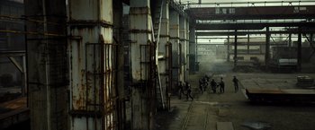 Movie still from “Spectral” (2016), directed by Nic Mathieu – A group of people walking down a train track next to a train station; Extreme Wide shot, High angle