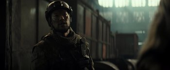 Movie still from “Spectral” (2016), directed by Nic Mathieu – A man wearing a helmet and a uniform; Close Up shot, Over the shoulder angle