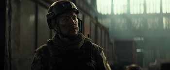 Movie still from “Spectral” (2016), directed by Nic Mathieu – A man wearing a helmet and holding a gun; Close Up shot, Low angle