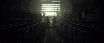 Movie still from “Spectral” (2016), directed by Nic Mathieu – Two people sitting on stairs inside a building; Extreme Wide shot, Low angle
