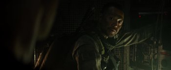 Movie still from “Spectral” (2016), directed by Nic Mathieu – A man in a uniform with a large backpack; Close Up shot, Over the shoulder angle