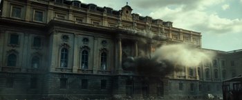 Movie still from “Spectral” (2016), directed by Nic Mathieu – Smoke billows out of a building on fire; Extreme Wide shot, Low angle