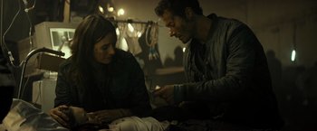 Movie still from “Spectral” (2016), directed by Nic Mathieu – A man and a woman looking at something on a table; Medium shot, Over the shoulder angle
