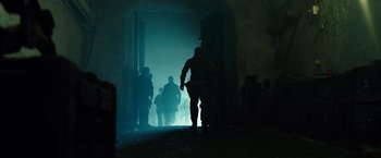 Movie still from “Spectral” (2016), directed by Nic Mathieu – A group of people walking down a dark hallway; Wide shot, Low angle