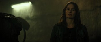 Movie still from “Spectral” (2016), directed by Nic Mathieu – A woman standing in front of a brick wall; Close Up shot, Over the shoulder angle