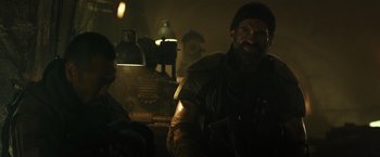 Movie still from “Spectral” (2016), directed by Nic Mathieu – A man with a beard is sitting next to another man with a beard; Medium shot, Over the shoulder angle