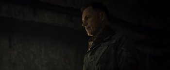 Movie still from “Spectral” (2016), directed by Nic Mathieu – A man standing in the dark looking to his left; Close Up shot, Over the shoulder angle