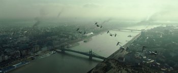 Movie still from “Spectral” (2016), directed by Nic Mathieu – Birds flying over a bridge over a body of water; Extreme Wide shot, High angle