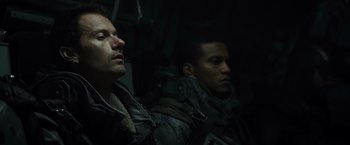 Movie still from “Spectral” (2016), directed by Nic Mathieu – Two men sitting next to each other in a dark room; Close Up shot, Low angle