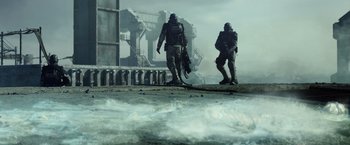 Movie still from “Spectral” (2016), directed by Nic Mathieu – Two soldiers walking on a beach near an ocean pier; Wide shot, Low angle