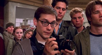 Movie still from “Spider-Man” (2002), directed by Sam Raimi – A group of young men standing around each other holding a camera; Close Up shot, Low angle