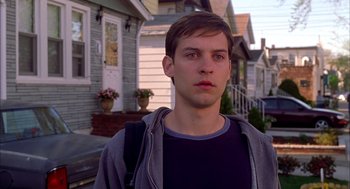 Movie still from “Spider-Man” (2002), directed by Sam Raimi – A young man standing in front of a row of houses; Close Up shot, Over the shoulder angle