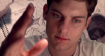 Movie still from “Spider-Man” (2002), directed by Sam Raimi – A young man holding his hand up in front of a drawing; Extreme Close Up shot, Overhead angle