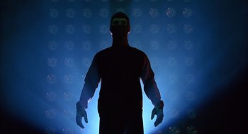 Movie still from “Spider-Man” (2002), directed by Sam Raimi – A man in a red jacket and a black mask is in the dark; Medium shot, Low angle