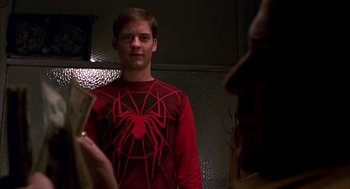 Movie still from “Spider-Man” (2002), directed by Sam Raimi – A young man in a red spider - man t - shirt; Medium shot, Over the shoulder angle