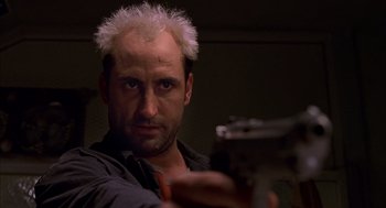 Movie still from “Spider-Man” (2002), directed by Sam Raimi – A man with white hair is holding a gun; Close Up shot, Low angle
